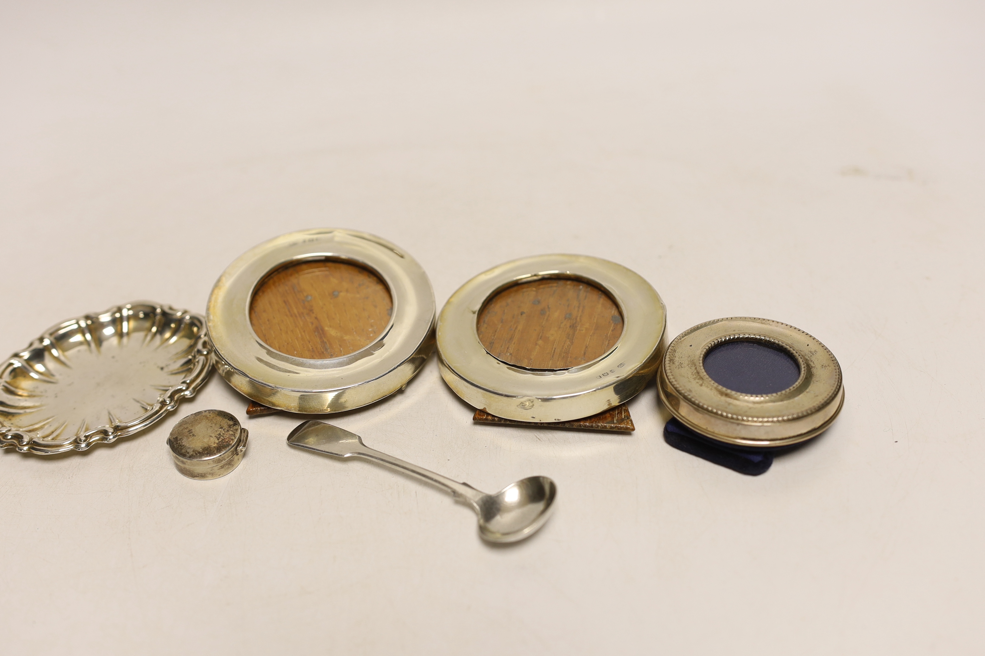 A small pair of George V silver mounted circular photograph frames, London, 1921, 75mm and four other items including a silver pill box and condiment spoon and small frame.